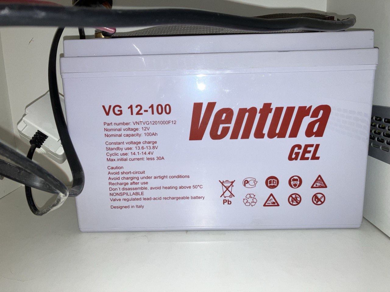 Крупный план гелевого аккумулятора Ventura GEL VG 12-100 (12V 100Ah) белого цвета. Видна этикетка с техническими характеристиками, током заряда и предупреждениями.