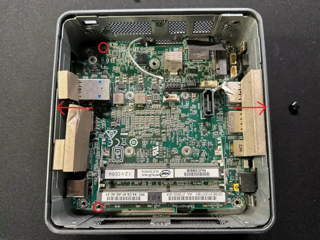 Демонтаж плати Intel NUC8: позначено два гвинти для викручування та стрілки для розпирання пластикового корпусу